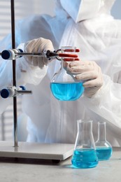 Photo of Scientist working with flask of light blue liquid in laboratory, closeup