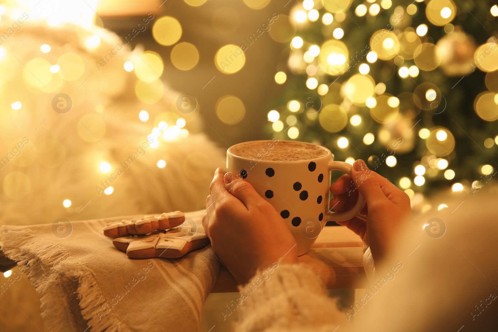 Photo of Woman with cup of hot drink and Christmas cookies at home, closeup