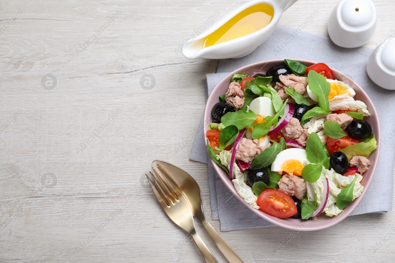 Photo of Bowl of delicious salad with canned tuna and vegetables served on white wooden table, flat lay. Space for text