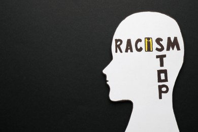 Photo of Human head cutout and phrase Stop Racism on black background, top view. Space for text