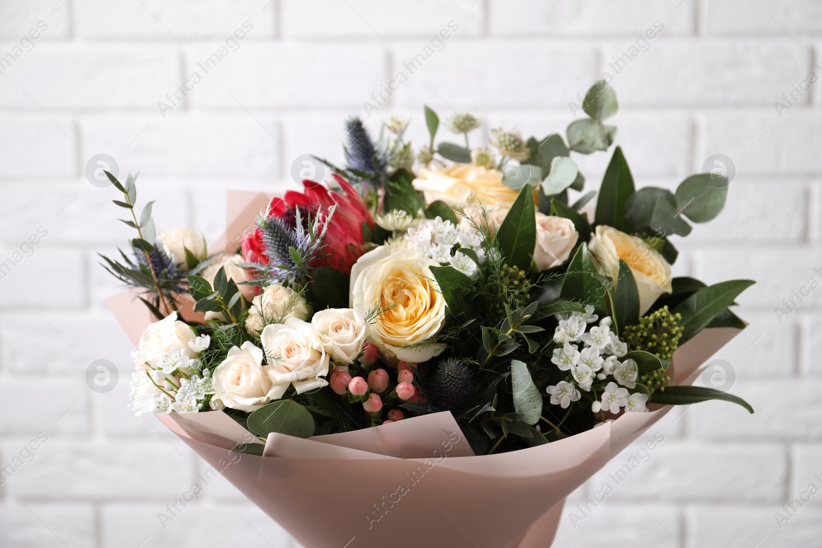 Photo of Beautiful bouquet with roses near white brick wall