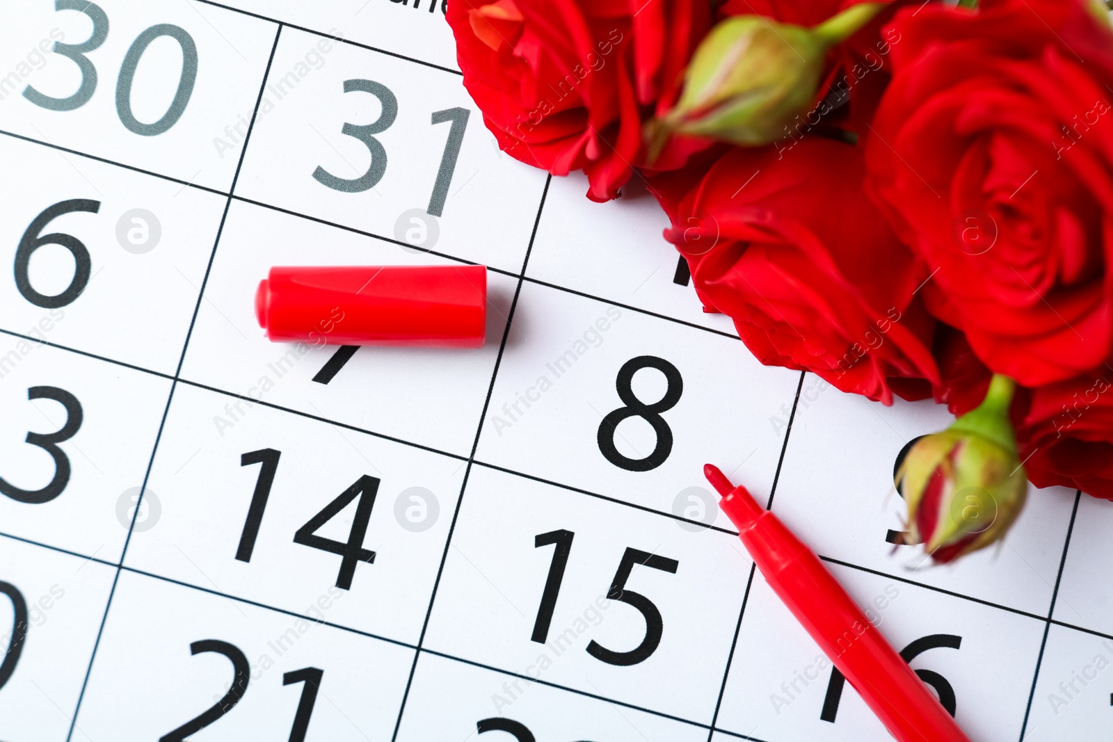 Photo of Roses and red marker on calendar near date 8th of March, above view. International Women's Day