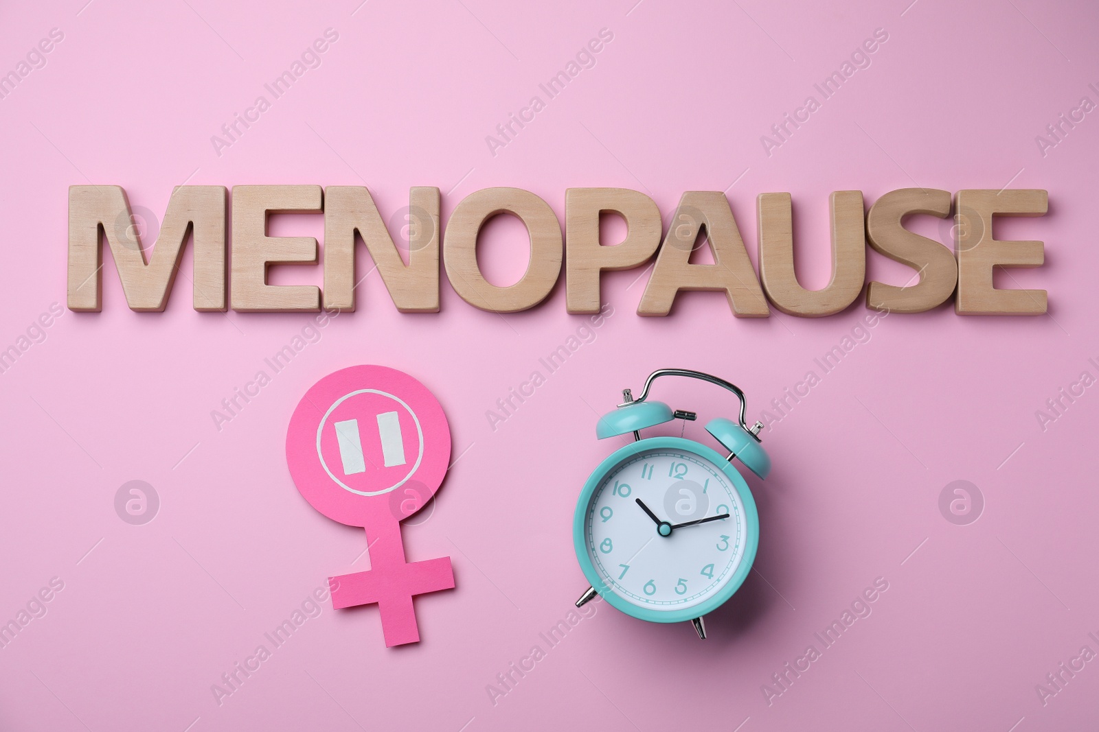 Photo of Word Menopause made of wooden letters, female gender sign and alarm clock on pink background, flat lay