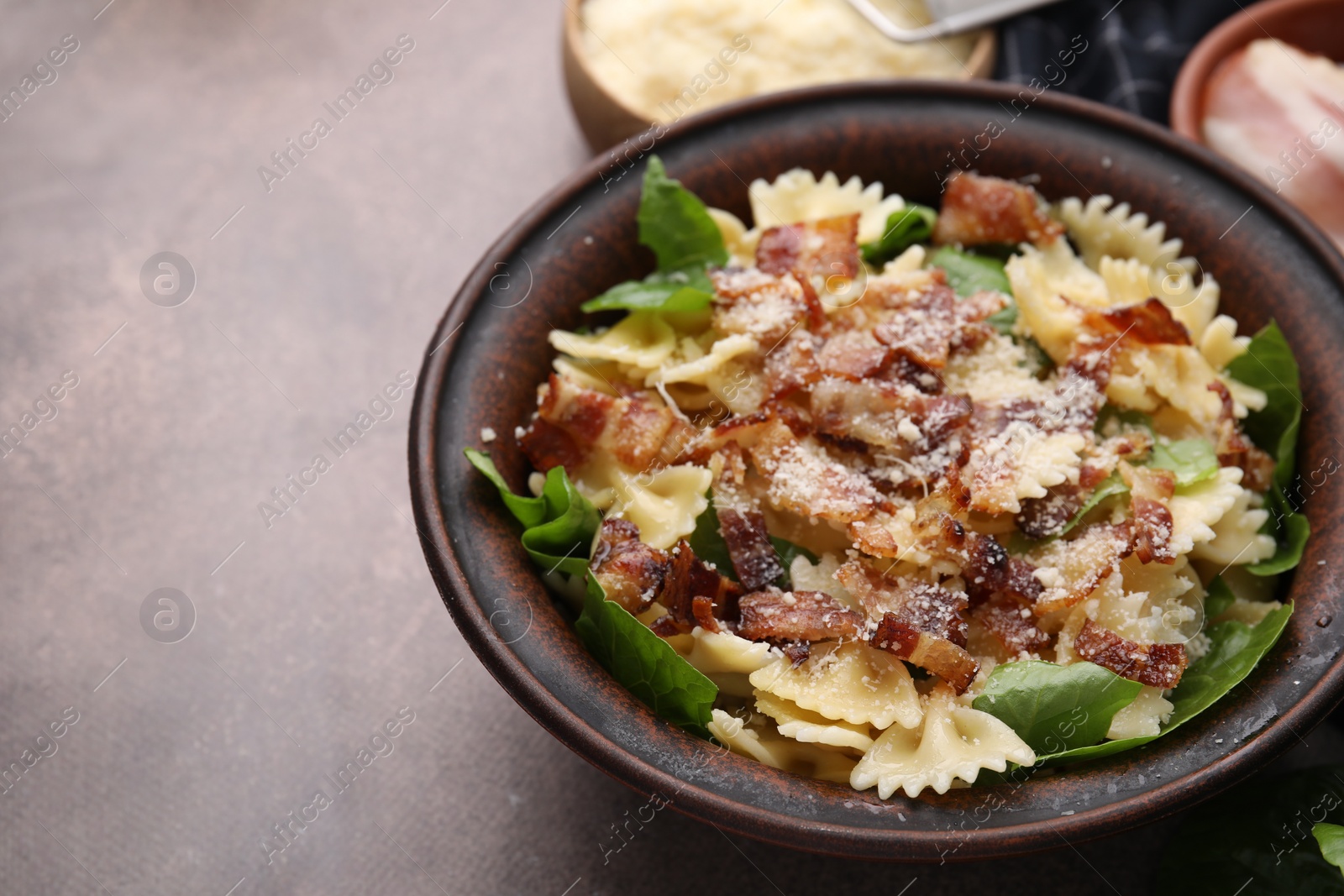 Photo of Tasty pasta with bacon and basil on brown table, space for text