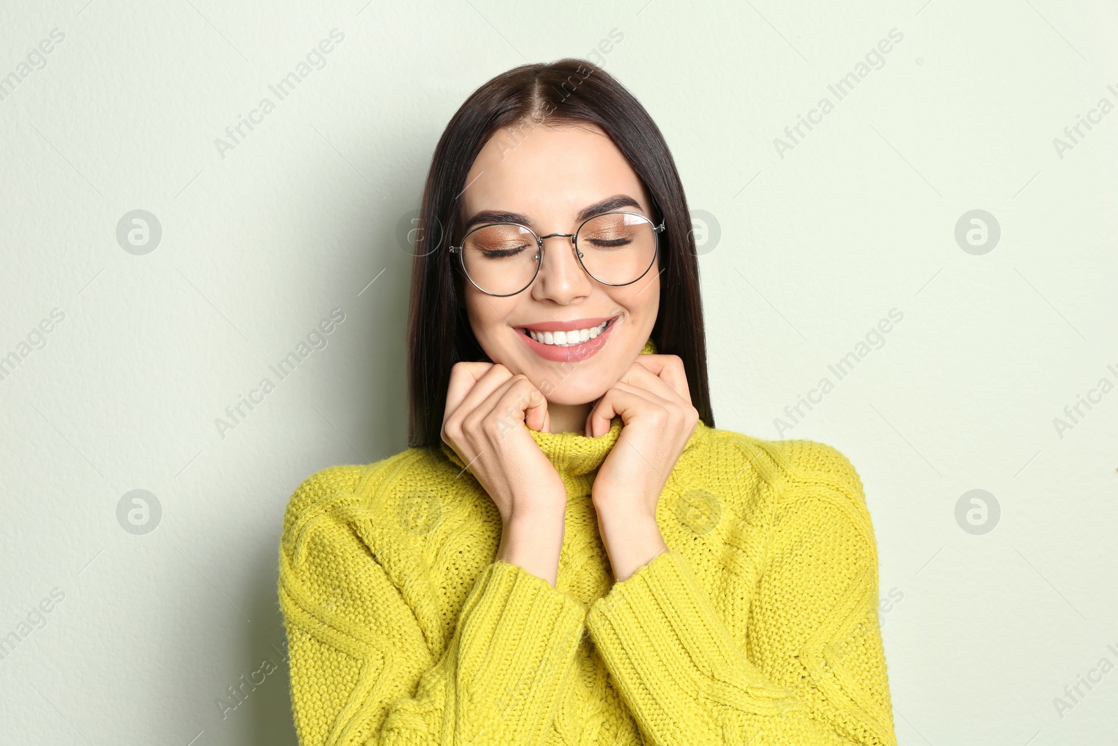 Photo of Young woman wearing warm sweater on light background. Winter season