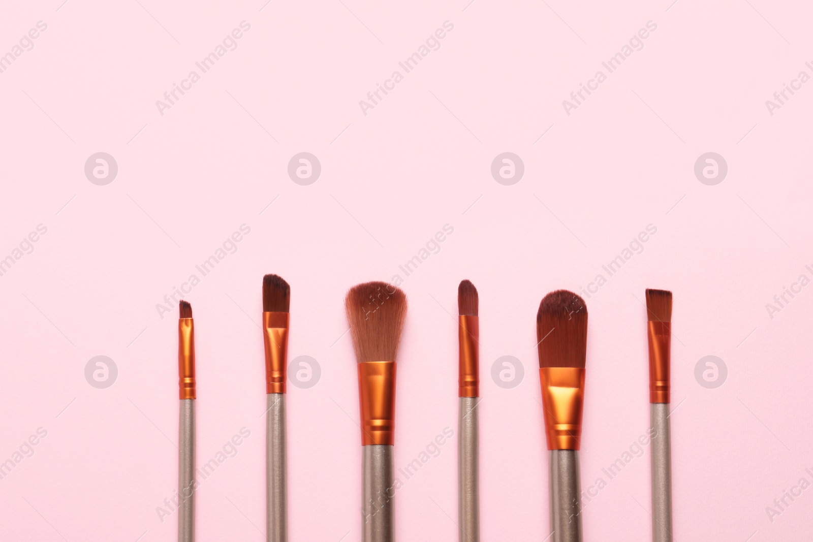 Photo of Set of makeup brushes on pink background, flat lay. Space for text