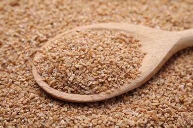 Photo of Wooden spoon with dry wheat groats, closeup