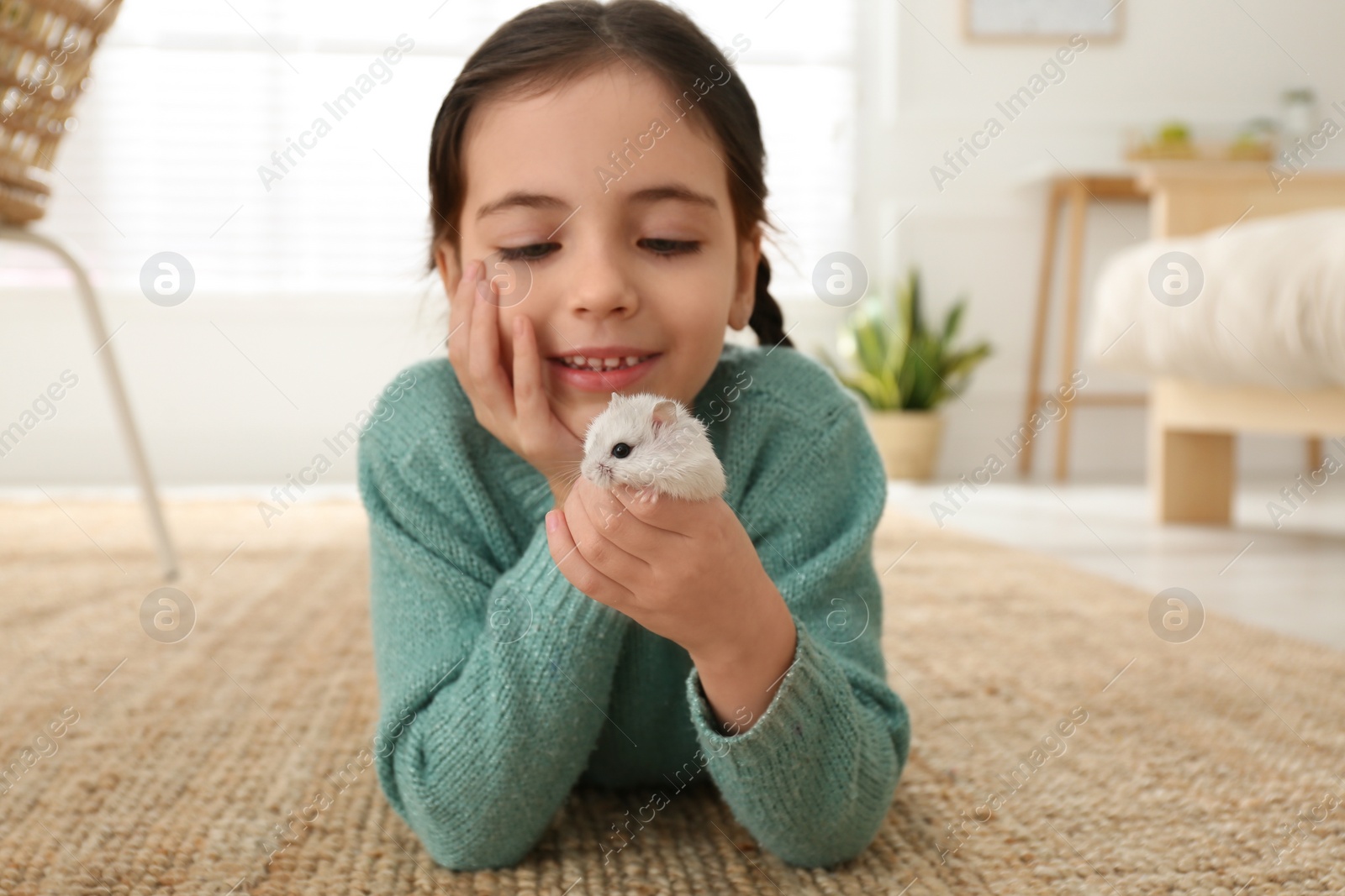 Photo of Little girl with cute hamster at home