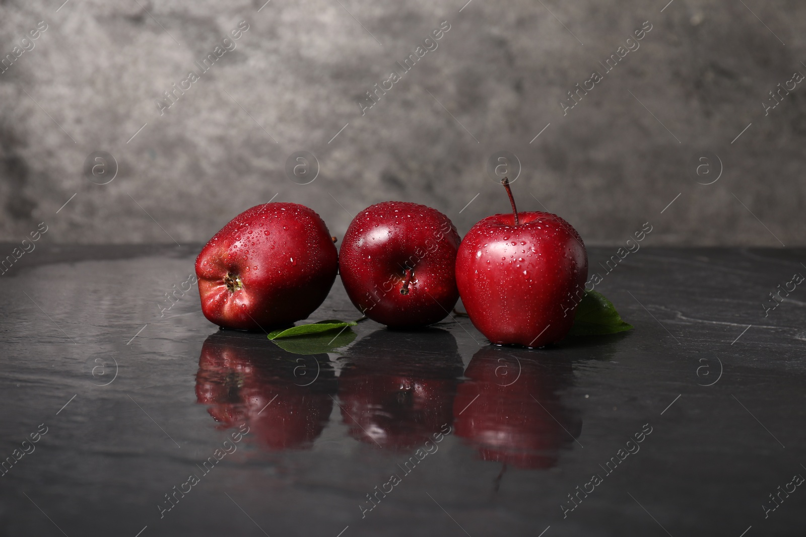 Photo of Wet red apples on dark grey table