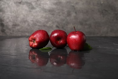 Photo of Wet red apples on dark grey table