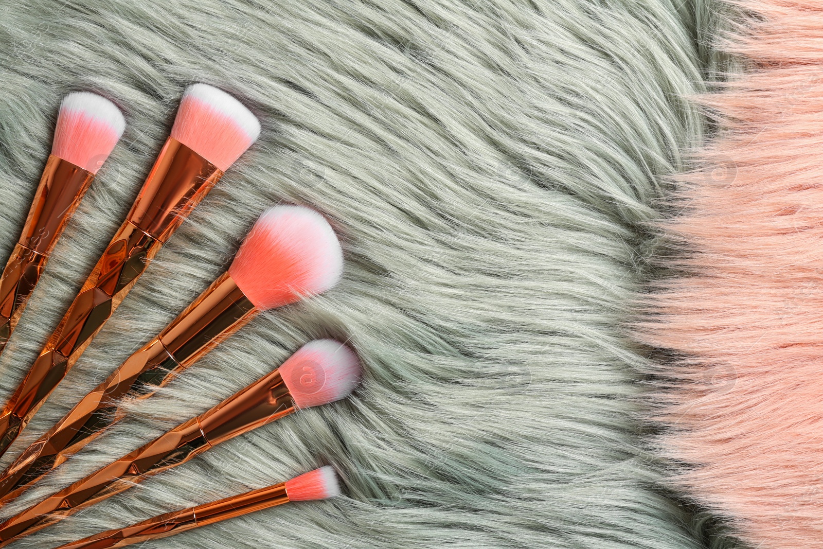 Photo of Set of professional makeup brushes on furry fabric, flat lay. Space for text