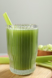 Photo of Glass of delicious celery juice and vegetables on wooden board, closeup