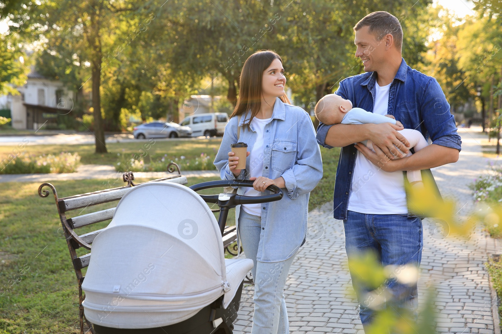 Photo of Happy parents walking with their baby in park on sunny day