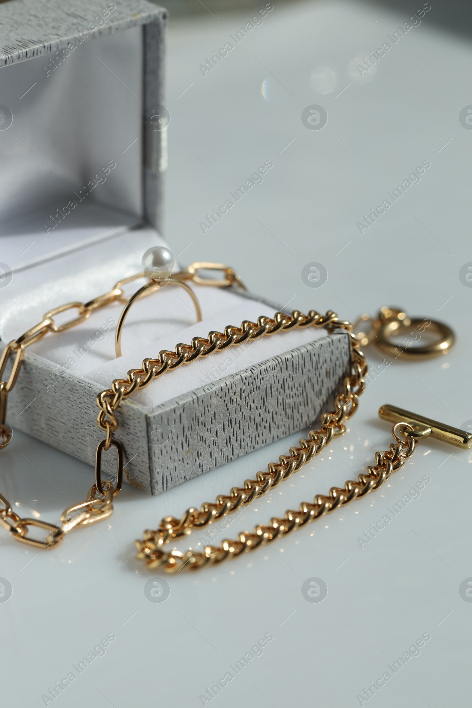 Photo of Metal chain and jewelry box with ring on white table