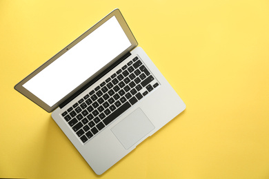 Photo of Modern laptop with blank screen on yellow background, top view