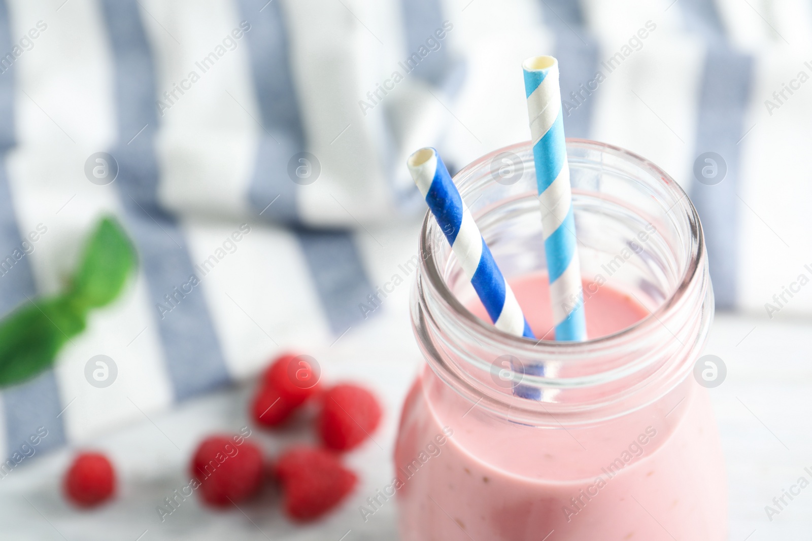 Image of Yummy raspberry smoothie in glass bottle on table, closeup 