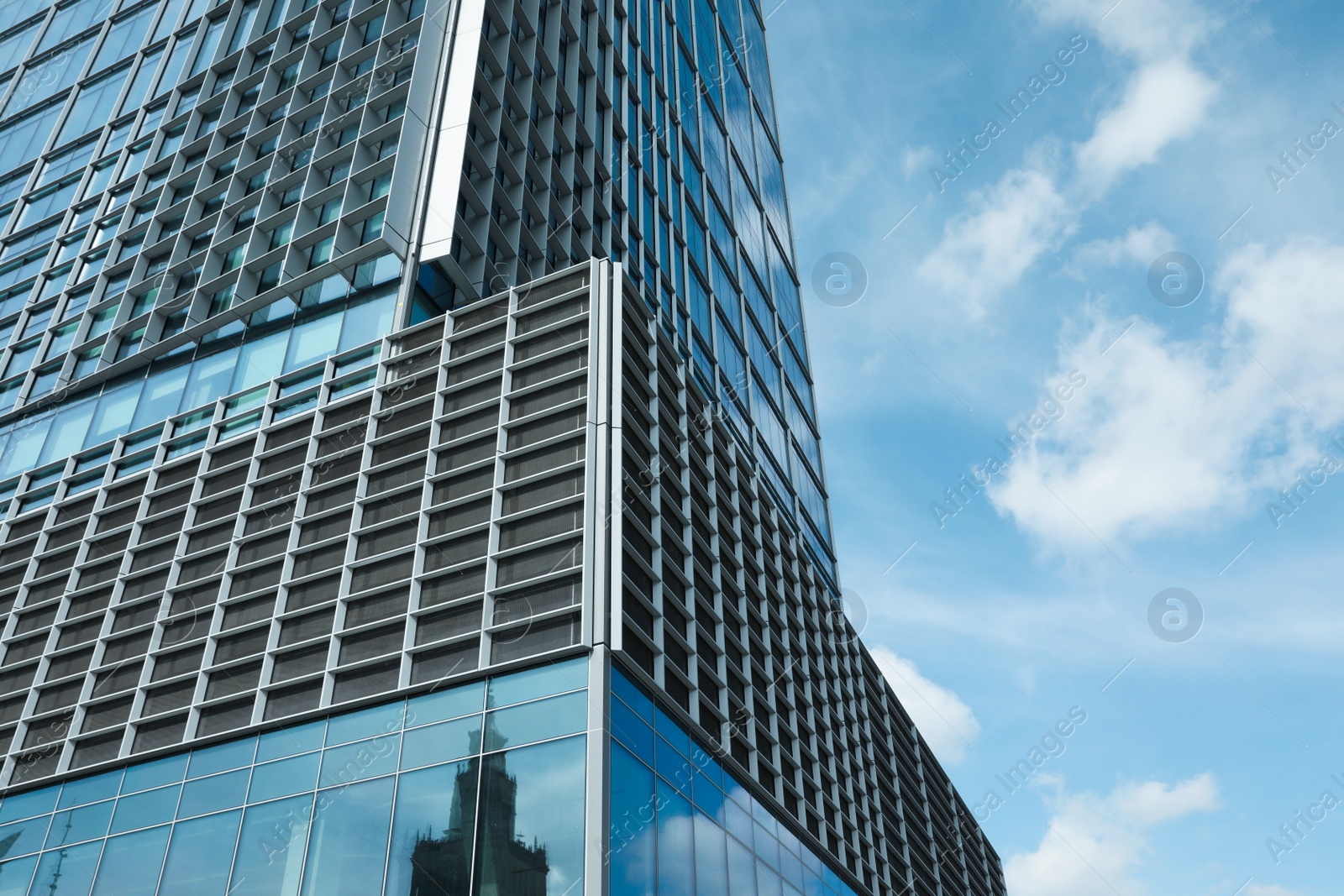 Photo of Modern skyscraper against blue sky with clouds, low angle view