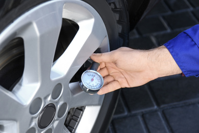 Mechanic checking tire air pressure at car service, closeup