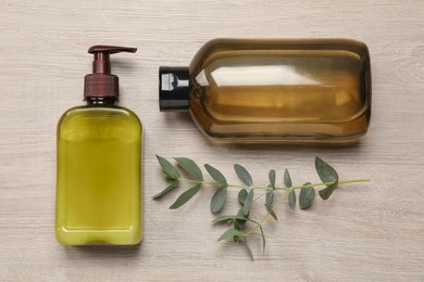 Bottles of shampoo and tree branch on white wooden table, flat lay