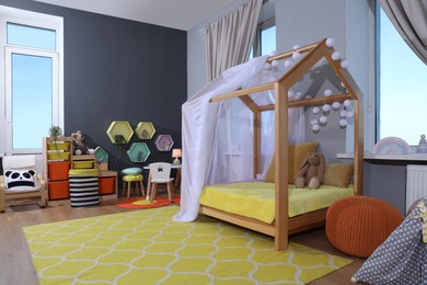 Photo of Stylish child room interior with comfortable house bed and toys