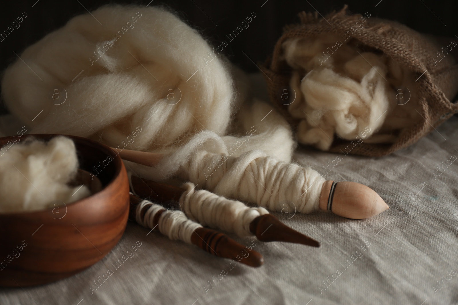 Photo of Soft white wool and spindles on table, closeup