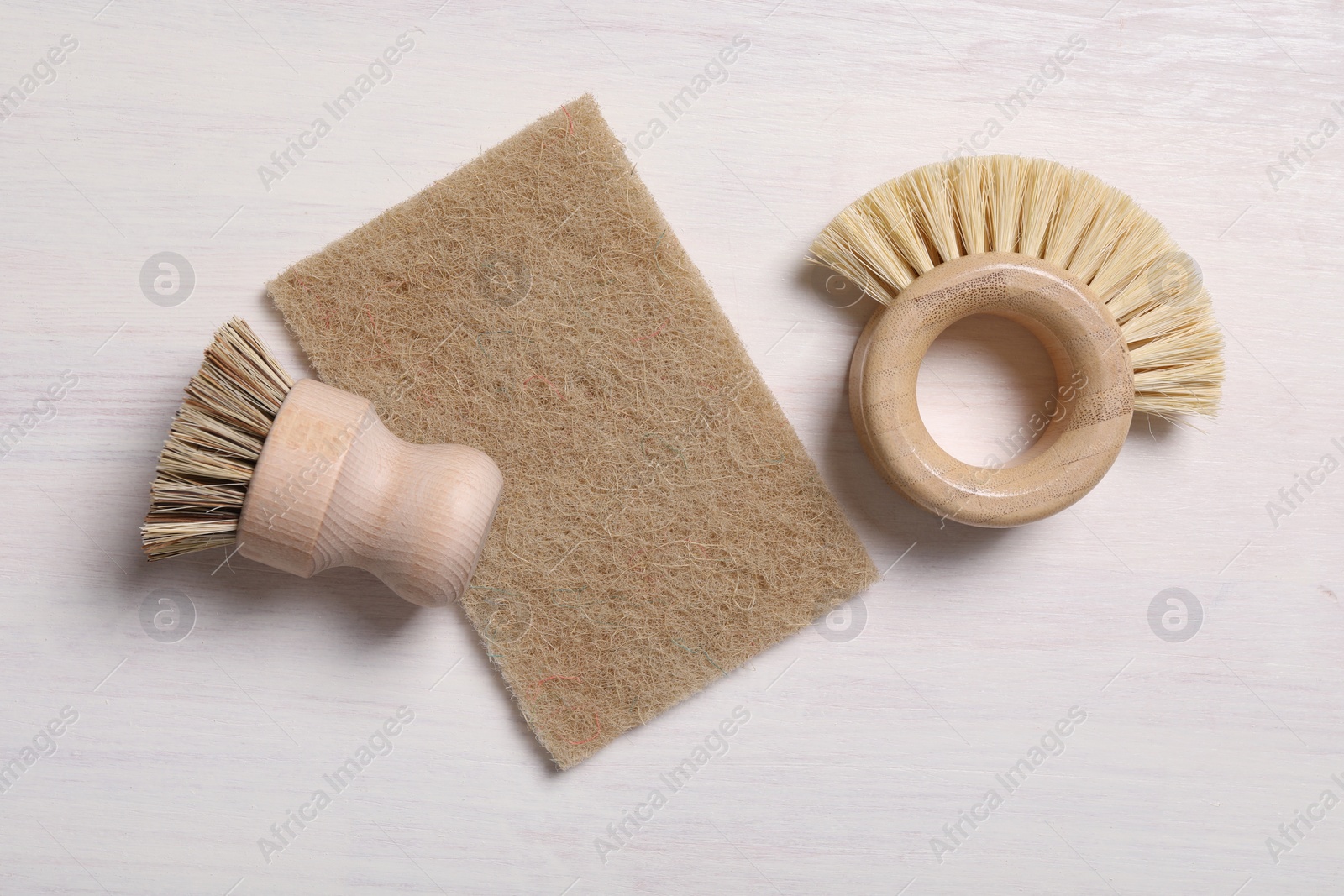 Photo of Cleaning brushes and sponge on light wooden table, top view