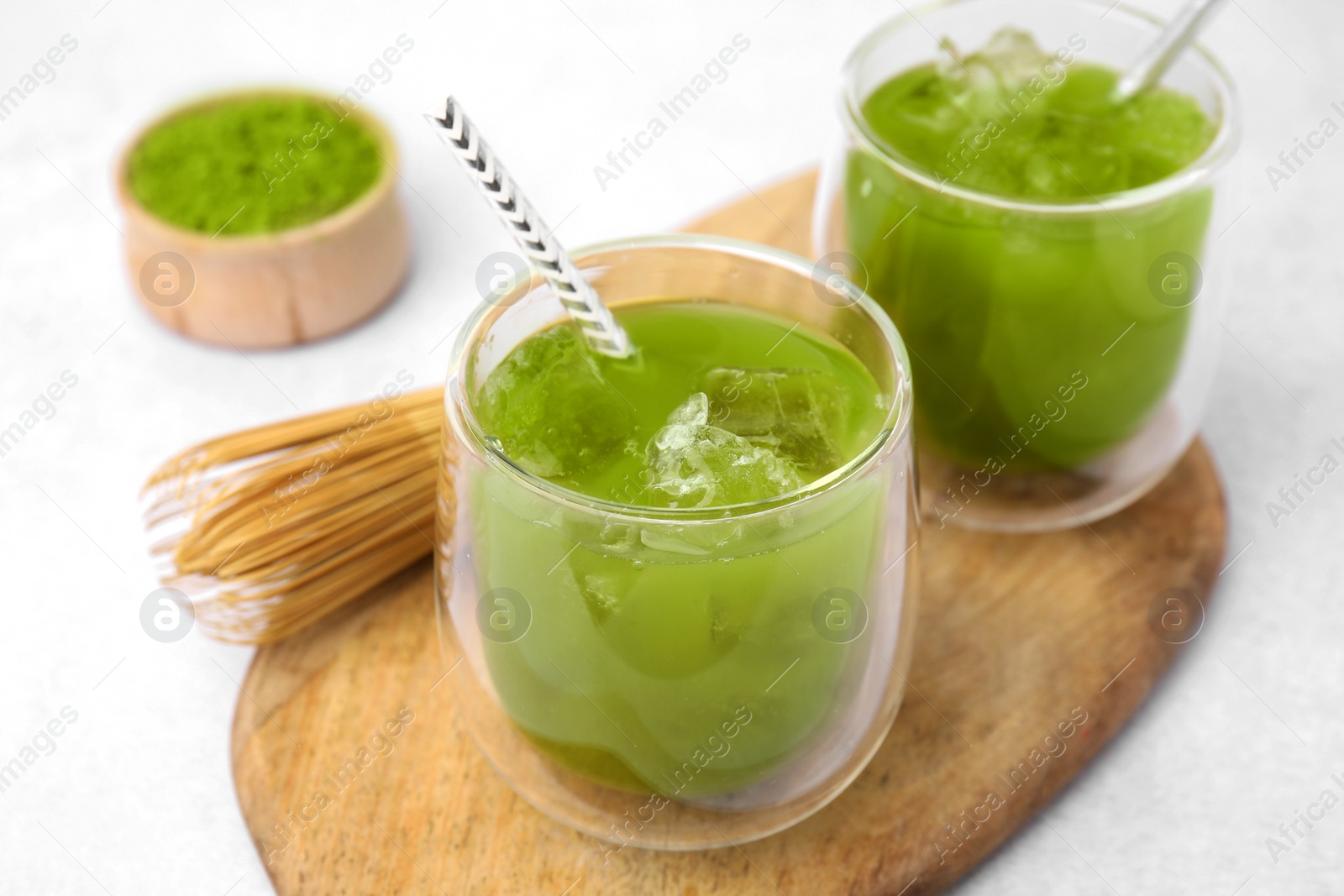 Photo of Delicious iced green matcha tea and bamboo whisk on white table, closeup