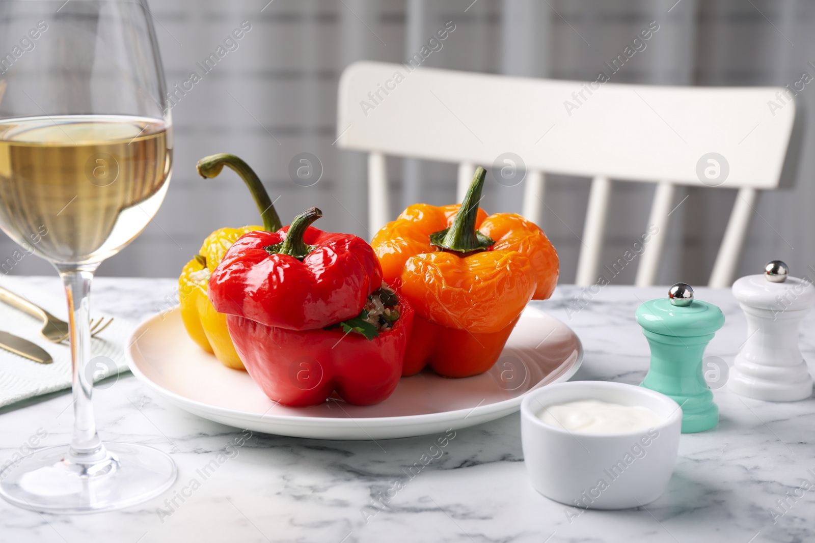 Photo of Tasty stuffed bell peppers served on white marble table in kitchen