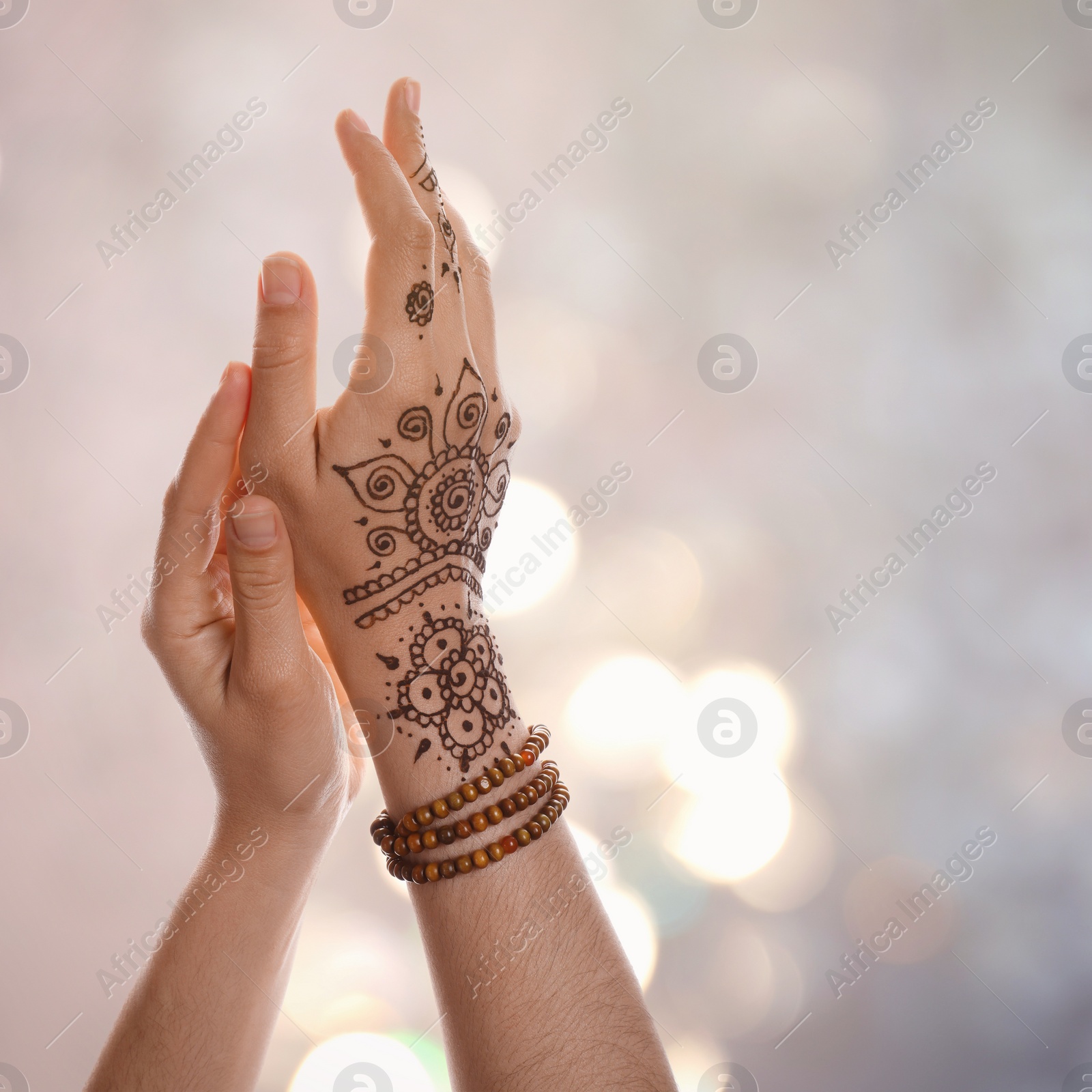 Image of Woman with henna tattoo on hand against blurred lights, bokeh effect