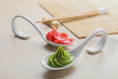 Photo of Spoons with swirl of wasabi paste and pickled ginger on white table