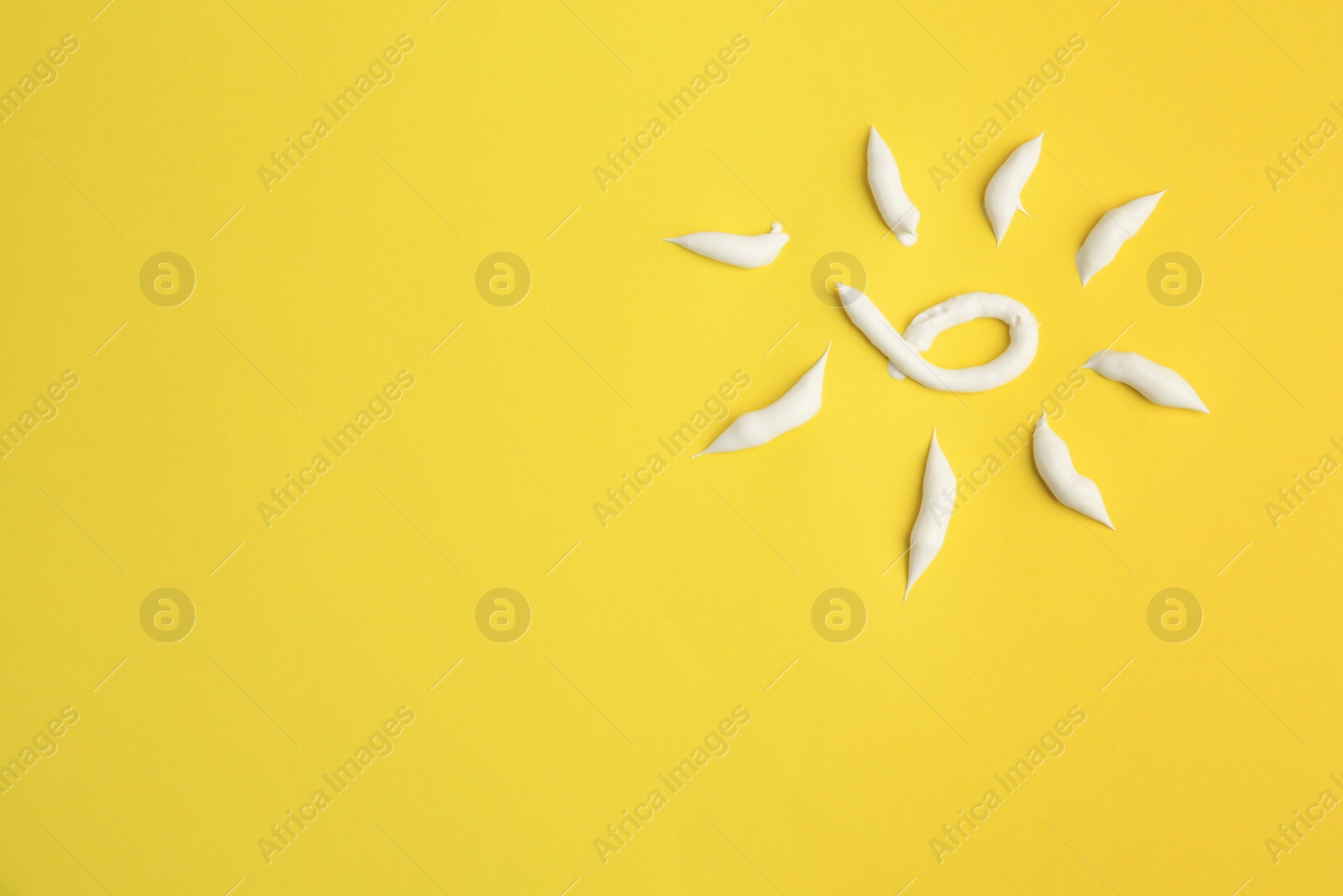 Photo of Drawing of sun with cream on yellow background, top view and space for text. Skin care and protection