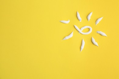 Photo of Drawing of sun with cream on yellow background, top view and space for text. Skin care and protection