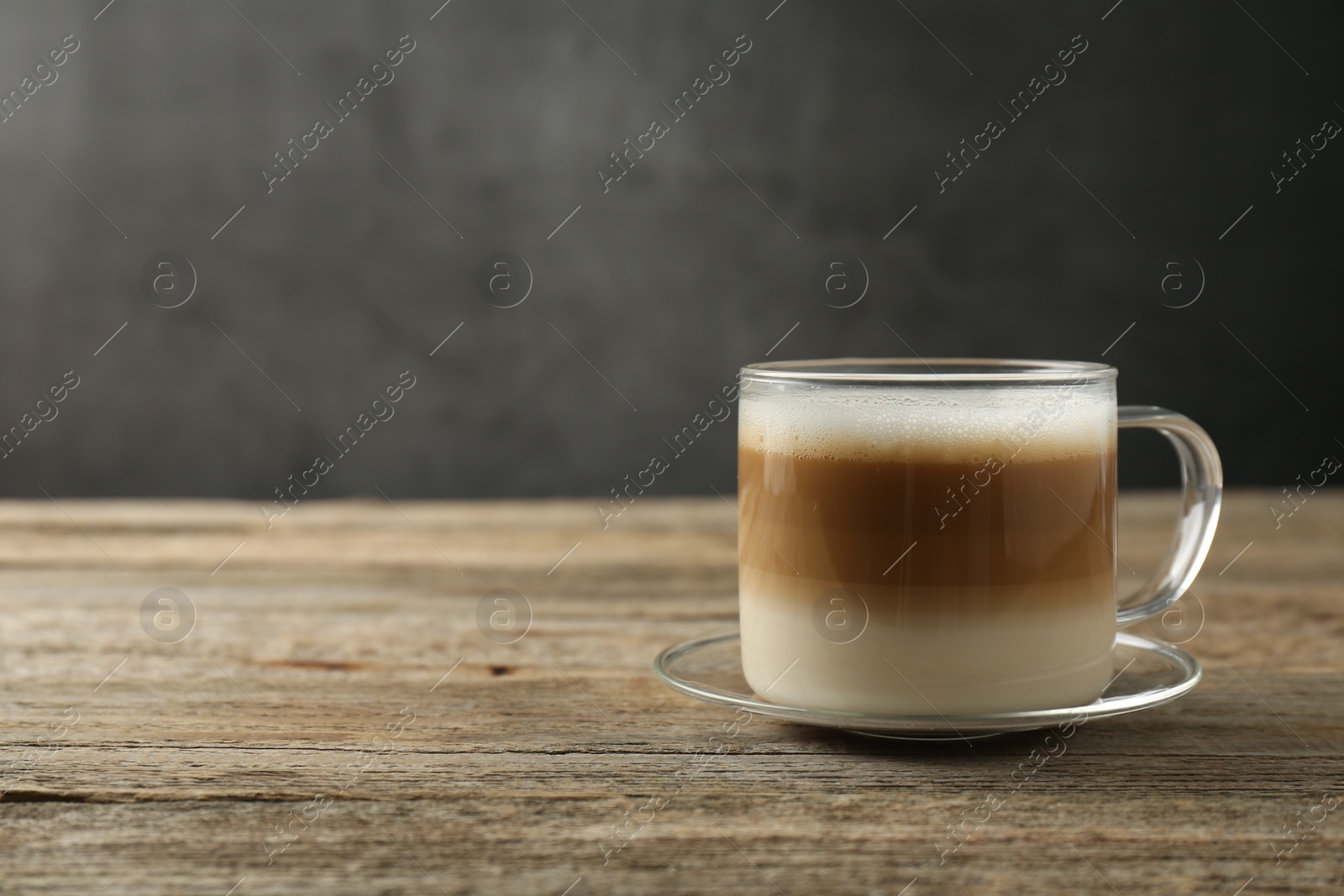 Photo of Aromatic coffee in glass cup on wooden table, space for text