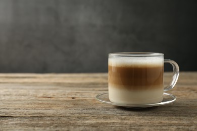 Photo of Aromatic coffee in glass cup on wooden table, space for text