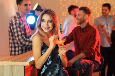 Photo of Beautiful young woman with glass of martini cocktail in bar, space for text