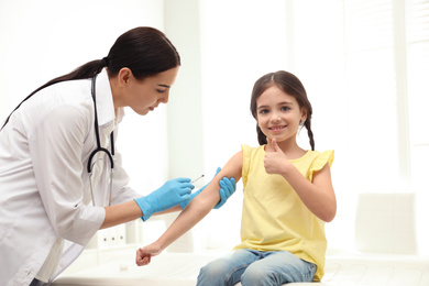 Photo of Doctor vaccinating little child in modern clinic