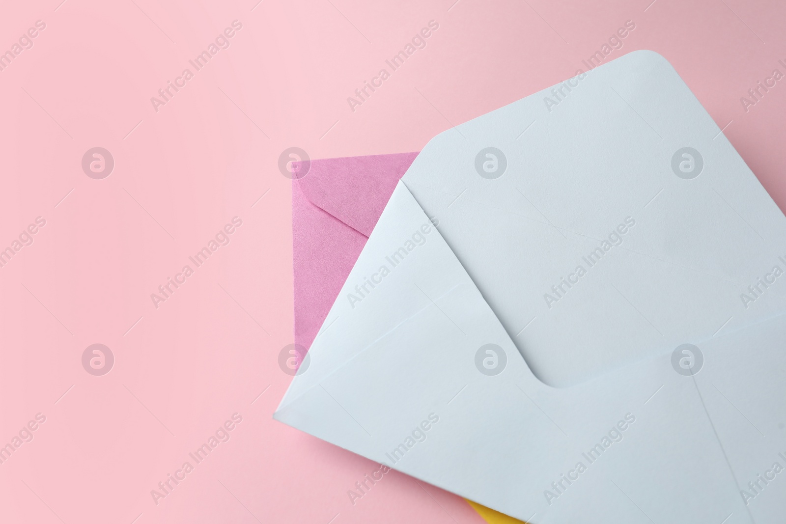 Photo of Colorful paper envelopes on pink background, top view. Space for text