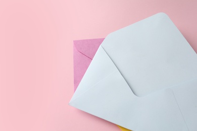 Colorful paper envelopes on pink background, top view. Space for text