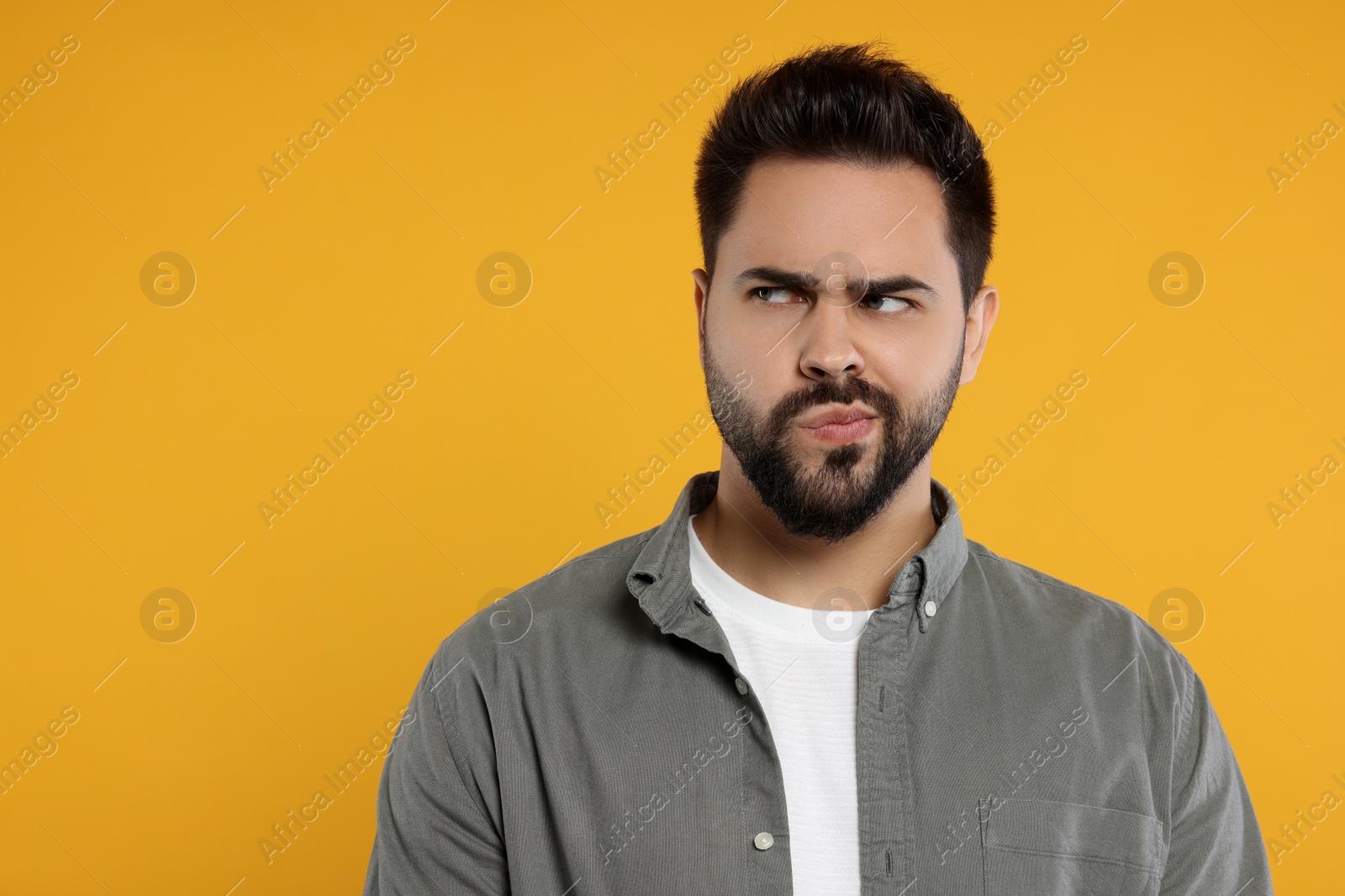 Photo of Resentful man on orange background. Space for text