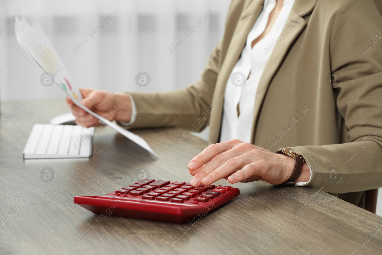 Photo of Professional accountant using calculator at wooden desk in office, closeup