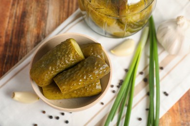 Photo of Bowl with tasty pickled cucumbers and ingredients on wooden table, flat lay