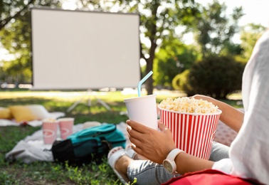 Photo of Woman with popcorn watching movie in open air cinema, closeup. Space for text