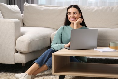 Happy woman working with laptop at coffee table in living room