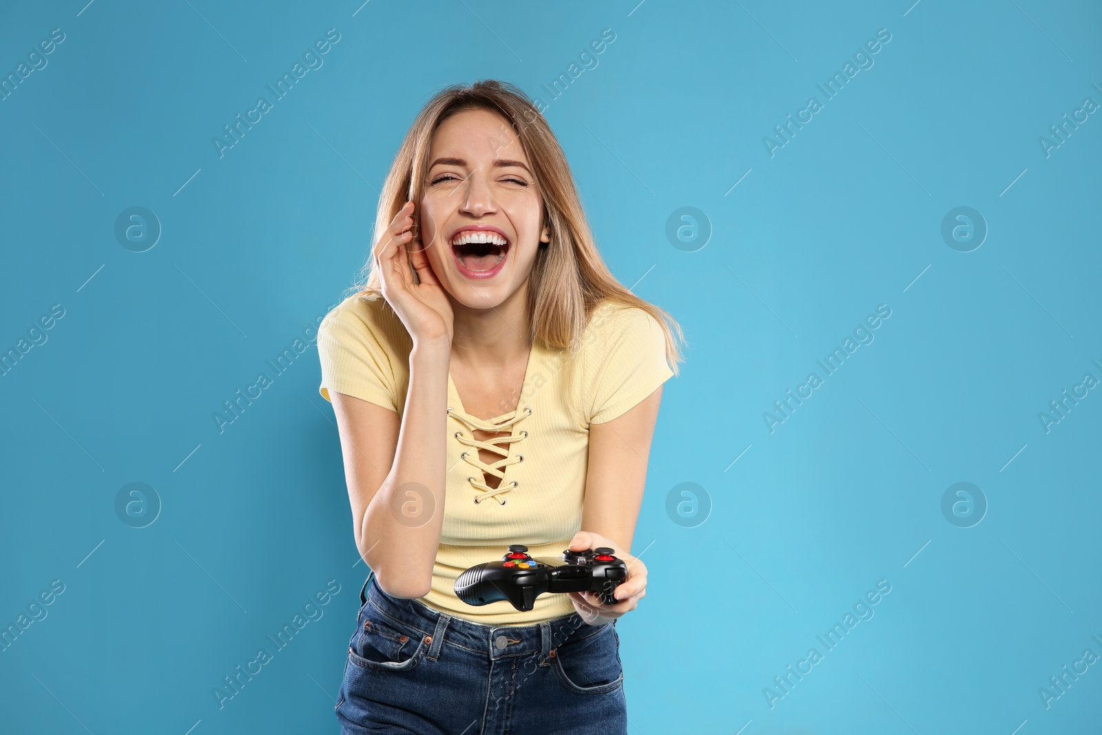 Photo of Emotional young woman playing video games with controller on color background. Space for text