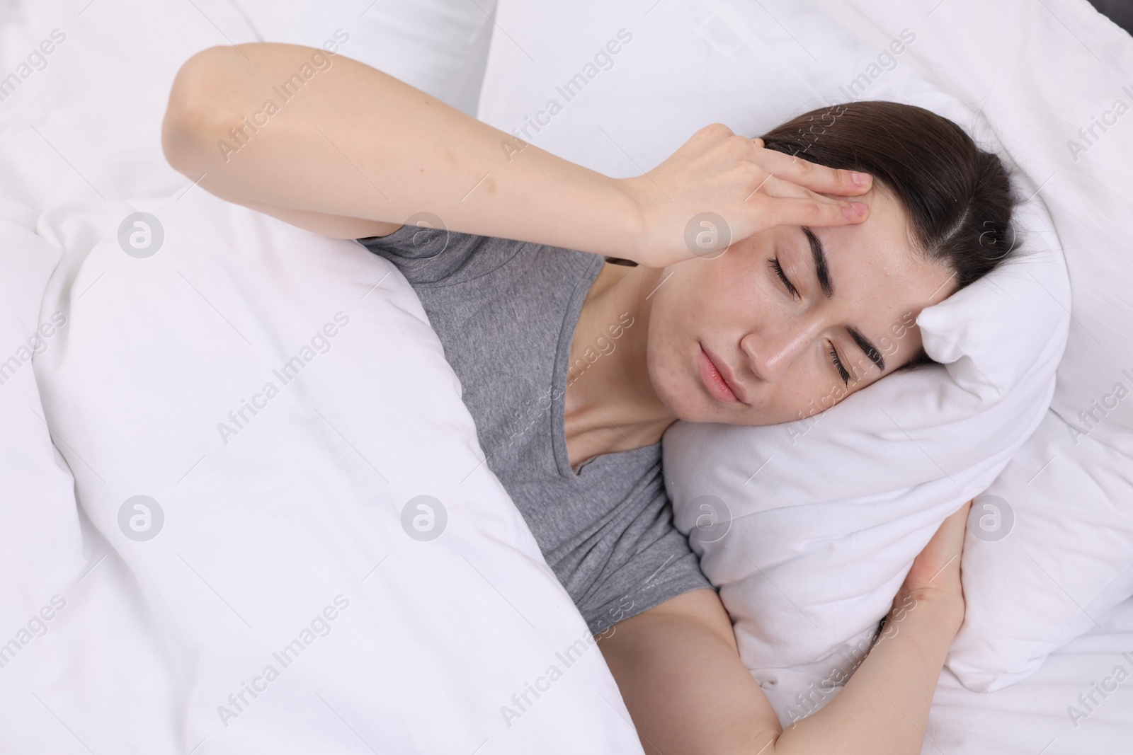 Photo of Sad woman suffering from headache in bed indoors