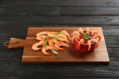 Photo of Delicious shrimp cocktail with tomato sauce served on black wooden table