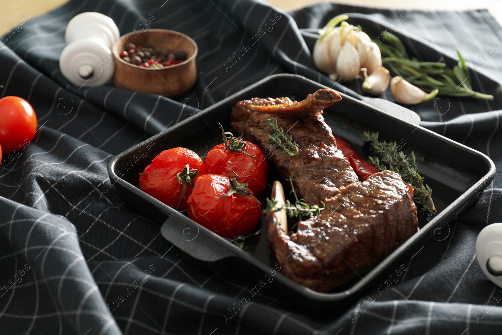 Photo of Delicious roasted ribs with tomatoes on table