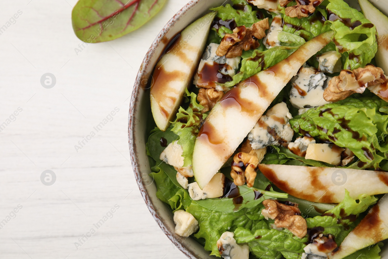 Photo of Delicious pear salad with sauce in bowl on light table, top view. Space for text