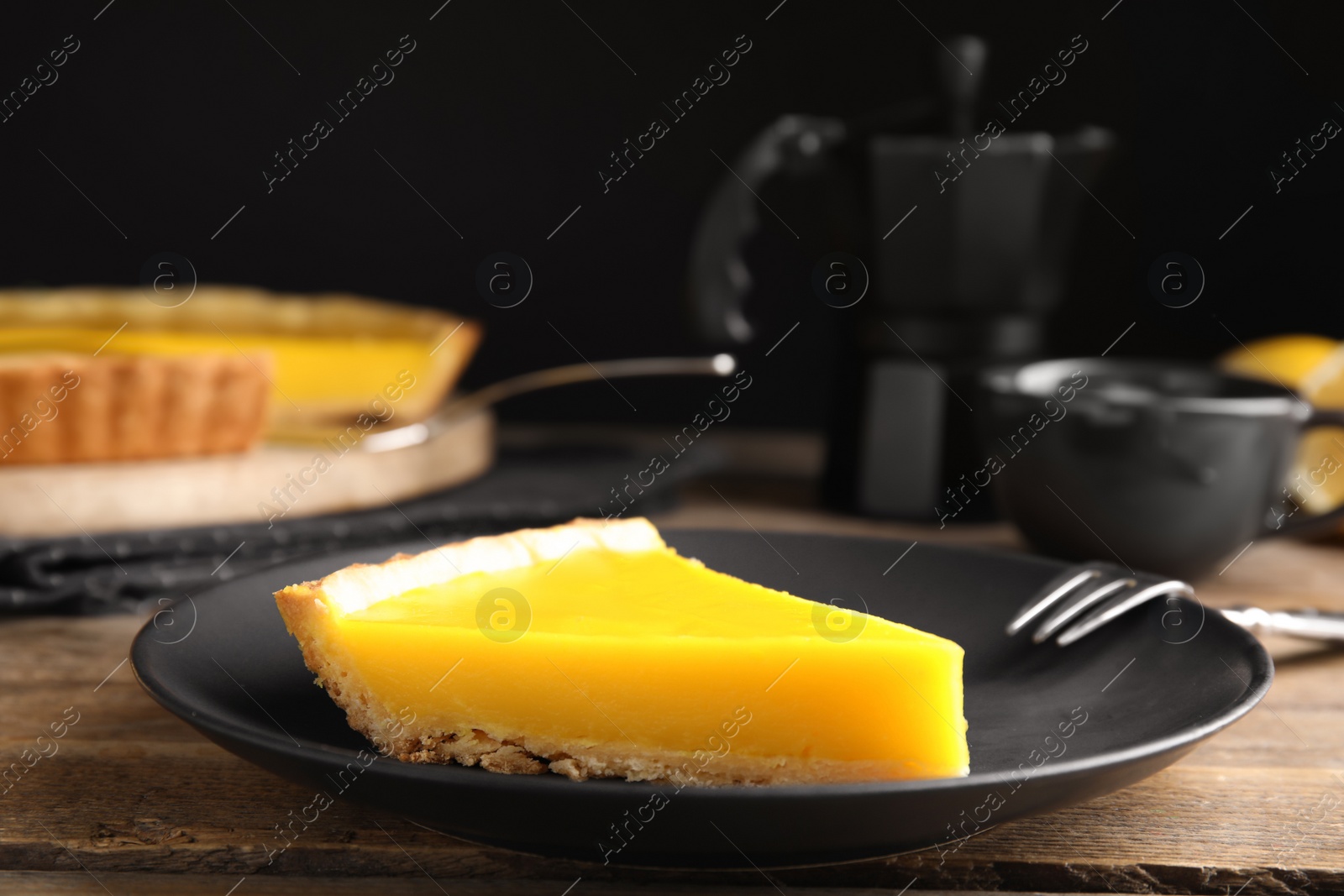 Photo of Slice of delicious homemade lemon pie on wooden table