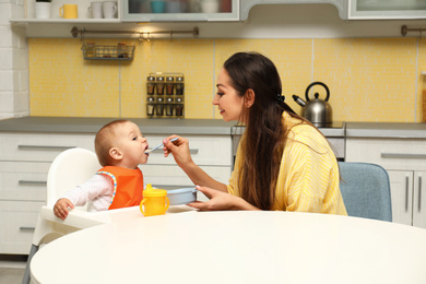 Young mother feeding her little baby at home